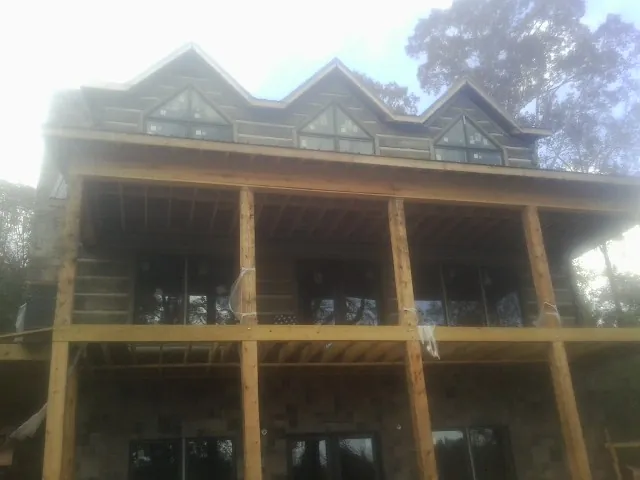 Dormers and porch framing on a large log home under construction — Roof Coating work by our crew in East Branch