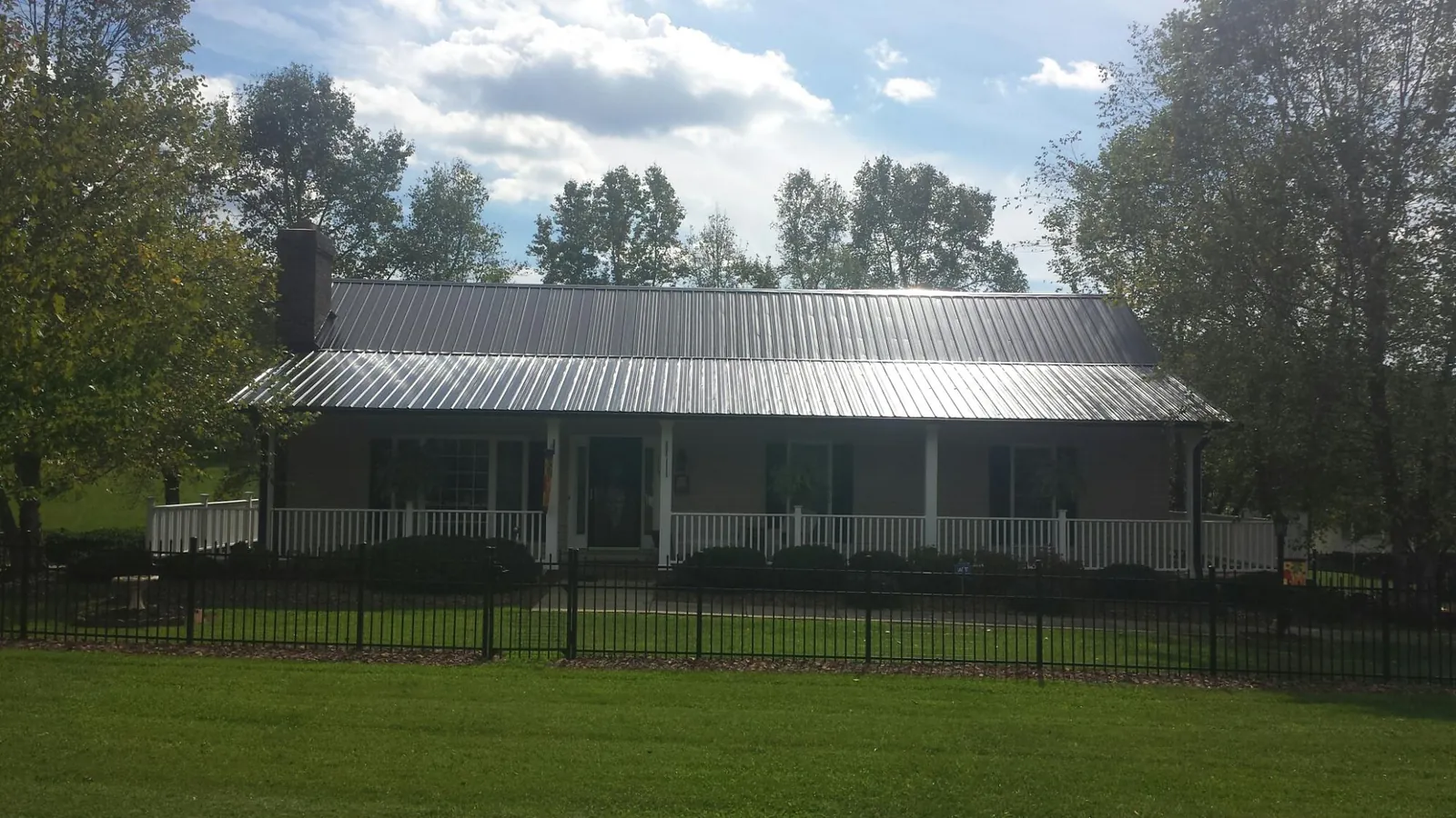 Gray metal roof on a brick ranch with a full width front porch — Gutter Guard Installation work by our crew in East Branch