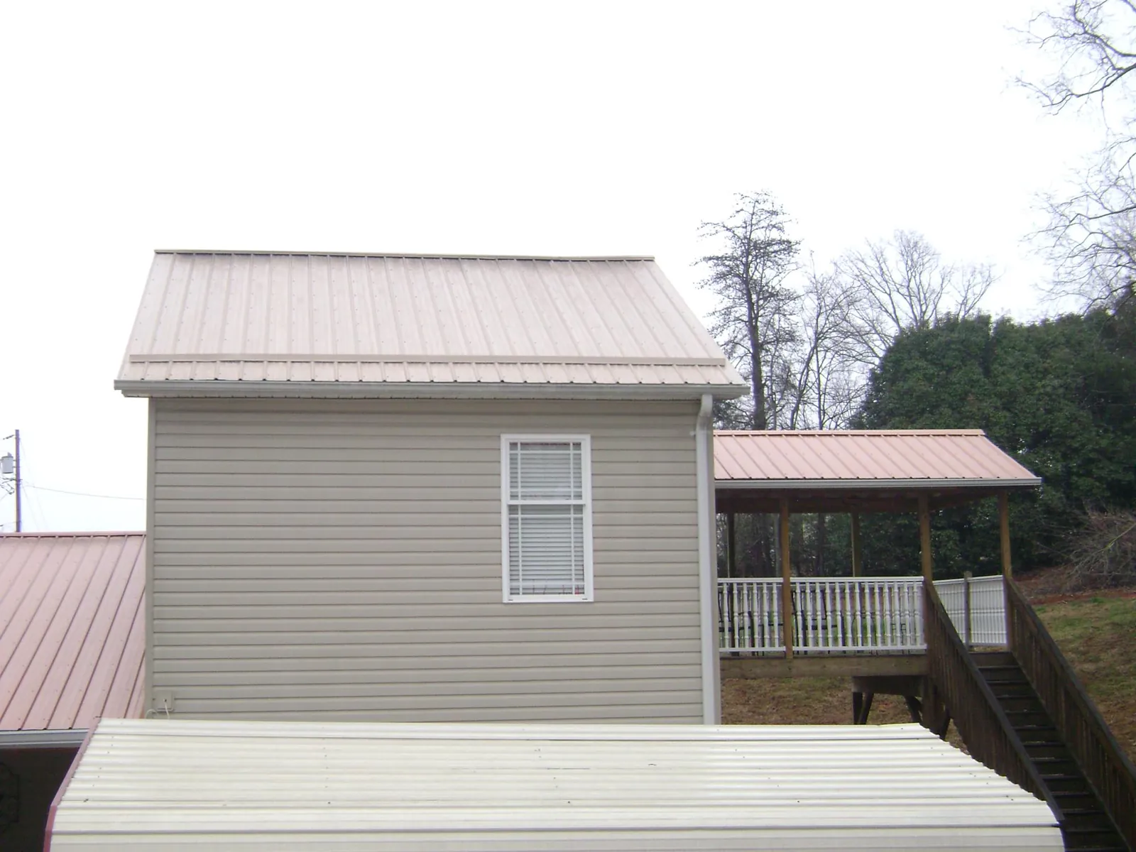 Tan metal roofs on a two story addition and attached porch in East Branch