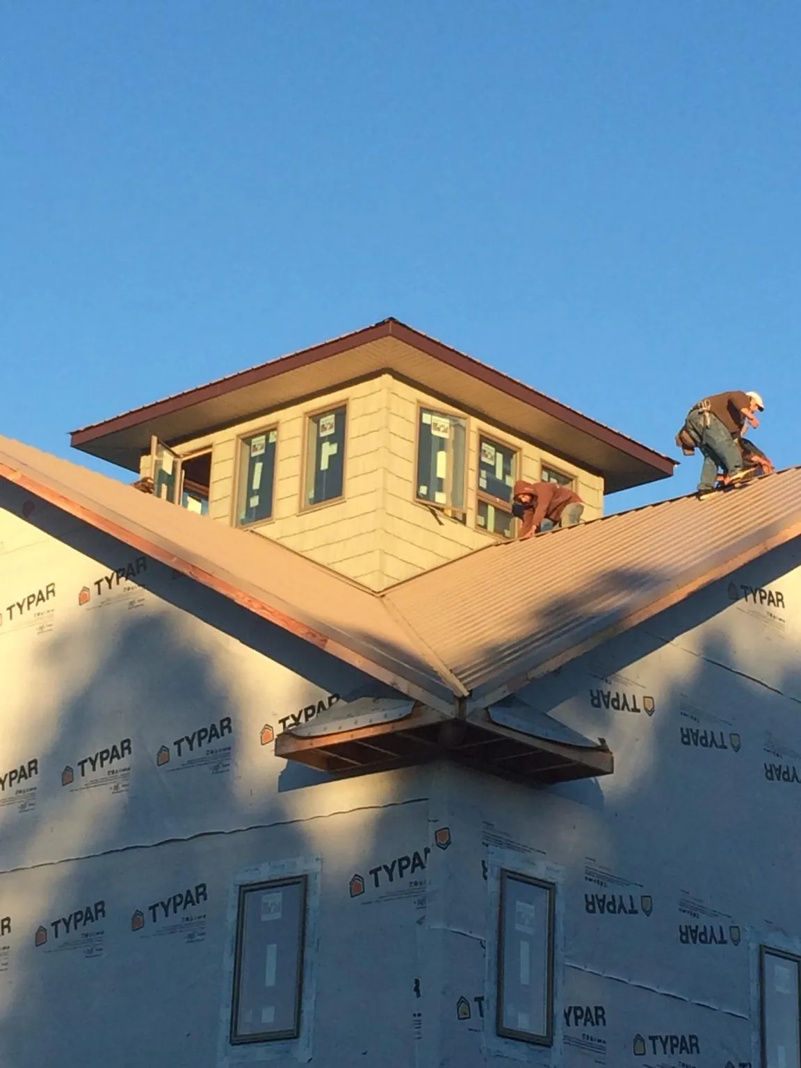 Roofers working around a rooftop cupola on a new metal roof at sunset — Roof Waterproofing in East Branch by Roofing Brothers